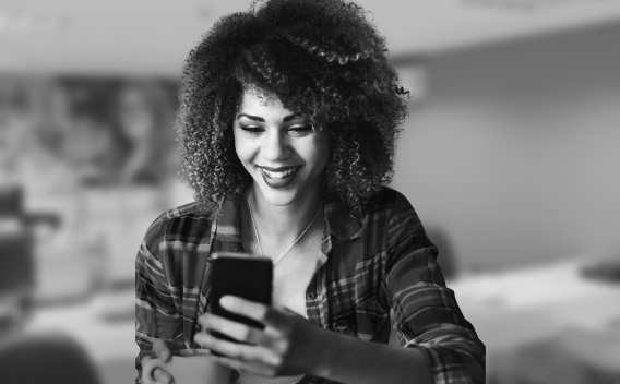 Retrato de uma jovem segurando o smartphone com as mãos e sorrindo